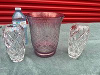 Group shot: pink cut crystal vase centered with two clear crystal bud vases