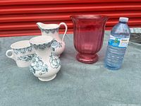 Group shot of red glass vase, three matching ceramic pieces and scale reference water bottle