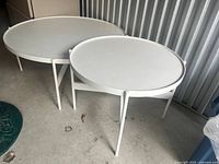 Pair of white metal round nesting tables standing side by side