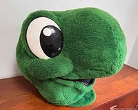 Left angled view of green plush Domer mascot head with large eye