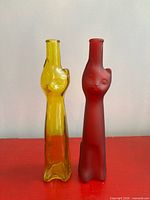 Front view of both yellow and red cat-shaped bottles standing side by side