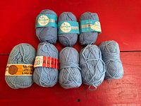 Group shot of all eight light blue skeins on red surface