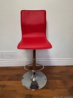 Front view of red barstool showing seat, pedestal and base