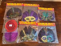 Overview of five feather masks and two packs spiral decor sealed in plastic