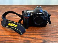 Front three-quarter view of Nikon D70s body with neck strap attached