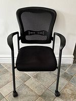 Front view of black mesh office chair with arms and casters