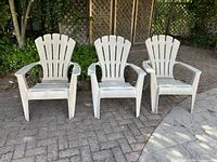 Full view of three matching resin Adirondack chairs placed side by side