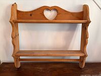 Full view of pine wall shelf showing two tiers, heart cutout, towel bar