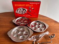 Open box with three plates, tongs in plastic