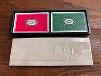 Two decks in black tray next to cream celluloid lid