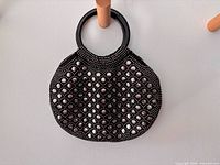 Full view of black studded handbag hanging from peg
