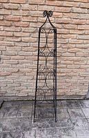 full view of wrought iron etagere against brick wall