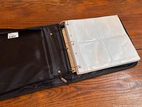 Binder opened showing three-ring mechanism, exterior pocket and sleeves inside