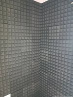 Corner wall covered with black pyramid acoustic foam tiles