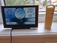 Front view of powered weather station display showing readings with sensor beside it