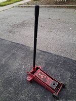 Full view of red floor jack with handle upright