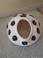Front view of white felt dome pet bed with entrance and black spots