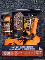 Front of package showing orange straps and ratchet mechanisms, capacity and size details visible