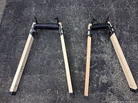 Two assembled adjustable sawhorse leg sets on pavement