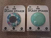 Front view of two sealed Sarina Splash Speakers in retail packaging showing colours and product name