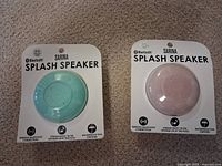 Front view of both packaged Sarina Splash speakers showing colors and branding