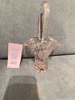 Front view of clear cut crystal basket vase showing floral pattern and handle