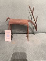 Side view of welded metal deer showing body, legs, patina, and scale tag