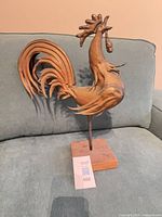 Left profile of copper rooster sculpture on wooden base