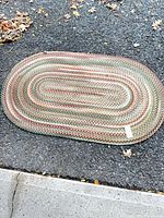 Full view of oval braided rug on asphalt surface