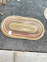 Full view of oval braided rug on pavement