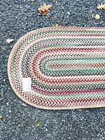 Full view of one end of oval braided rug showing pattern and colours