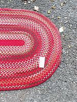 Full view of oval braided rug on pavement