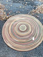 Full view of round braided rug on asphalt surface