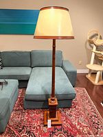 Full view of wooden floor lamp with shade beside sectional sofa