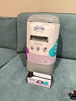 Front view of sealed Litter Genie Easy Roll pail beside boxed refill
