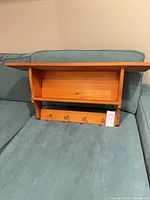 Front view of pine wall shelf showing top shelf, mid shelf, and four pegs