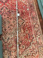 Full view of entire barbell laid on rug showing length and straight shape