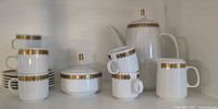 Full set showing coffeepot, creamer, sugar, stacked cups and saucers