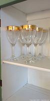 Five gold-rim wine goblets on shelf