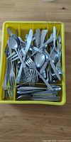 Yellow tray filled with assorted stainless flatware