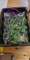 Black tote filled with assorted green, grey and blue K'Nex rods, connectors and purple track tubing