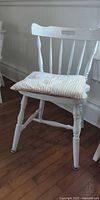 Side view of one chair showing white paint, turned legs, striped cushion