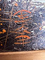 Close-up of red artist signature on textured black paint