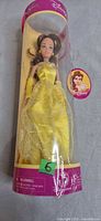 Full view of Belle doll in cylindrical Disney Store package