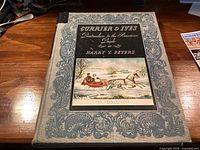 Front cover of grey cloth hardcover displaying title, decorative border, and color illustration