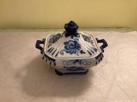 Sugar bowl with lid on showing floral design, handles, rose finial
