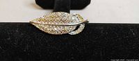 Front view of rhinestone leaf brooch on display bar