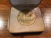Medal in open presentation case, obverse with Assembly building visible