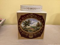 Front view showing countryside estate scene framed by maroon and gold cartouche