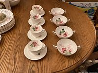 Full lot showing 4 teacups on saucers and 4 cream soup bowls